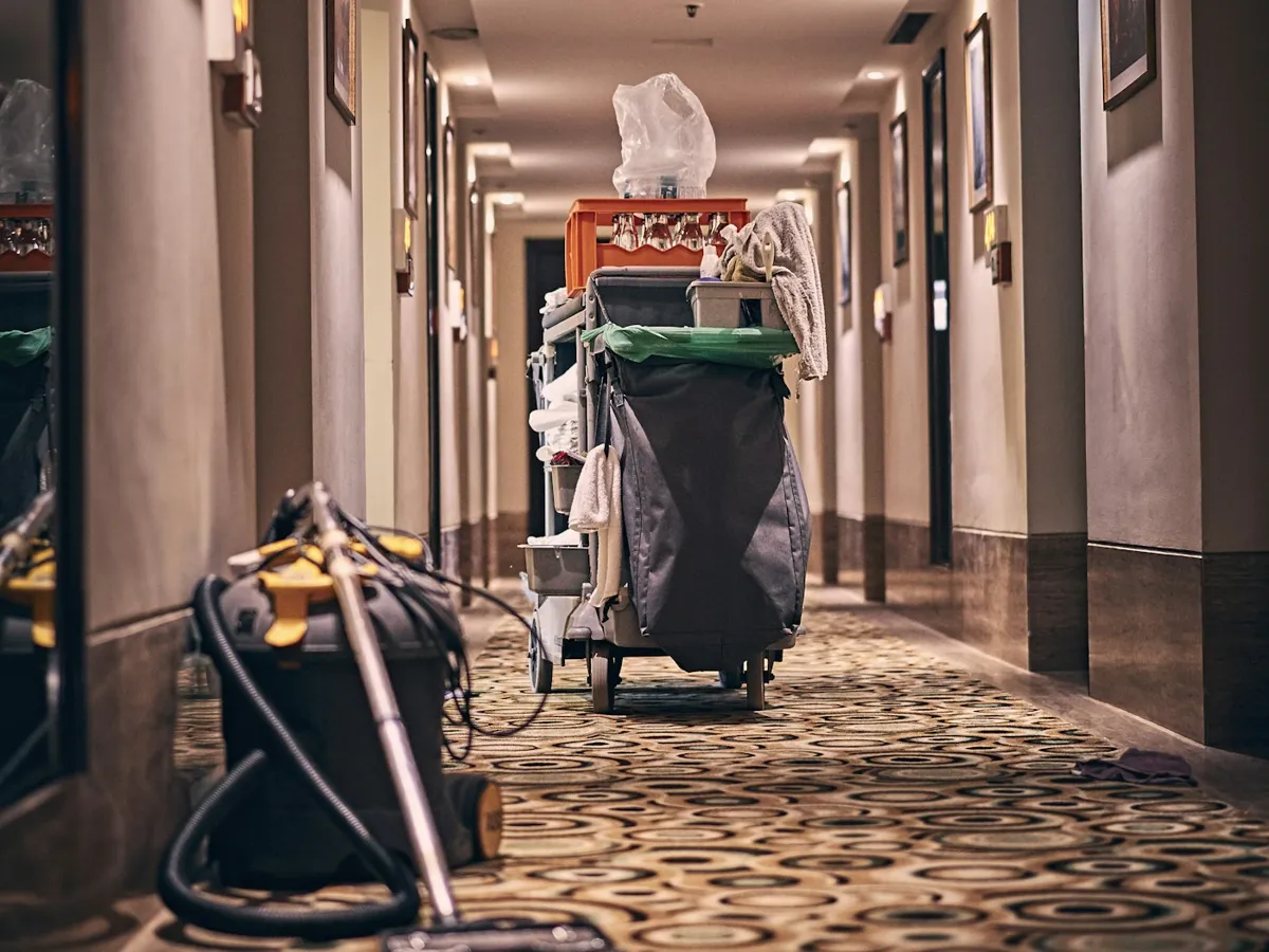 Vacuum and cleaning cart in a long carpeted hallway