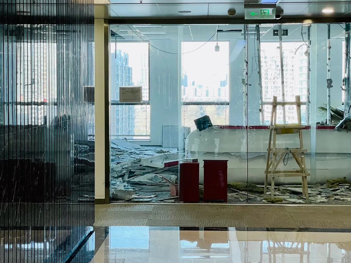 Office space mid-renovation with construction debris behind glass partitions