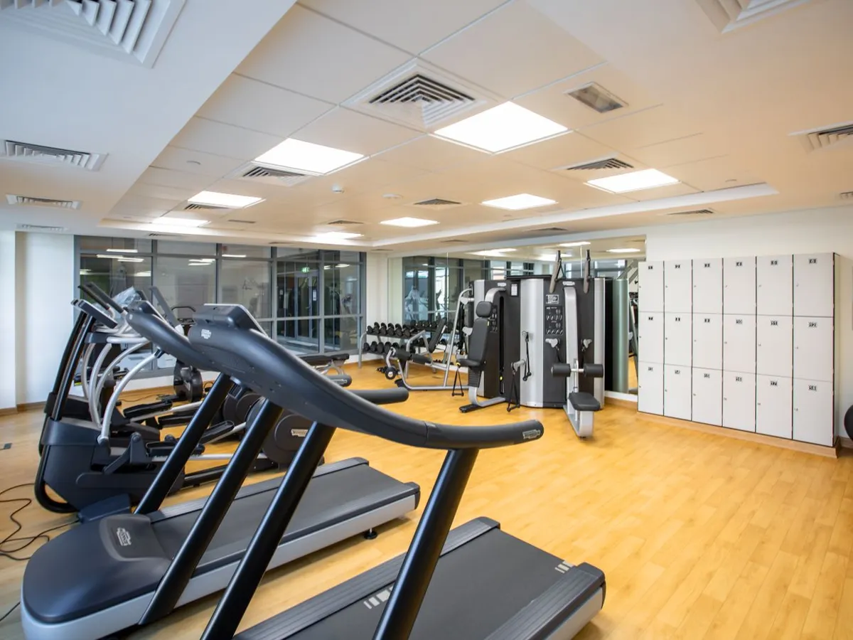 Bright, clean gym with treadmills, weight machines, and lockers