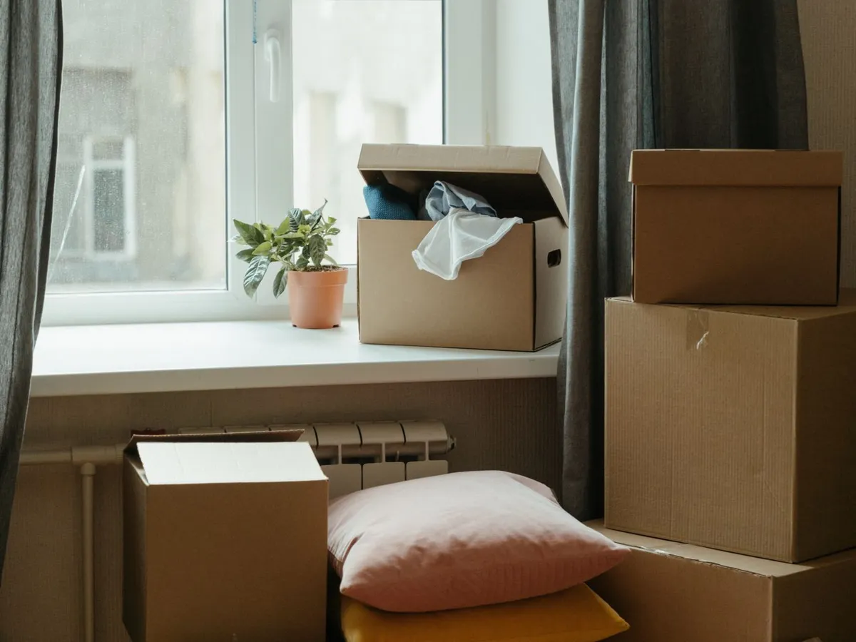 Moving boxes stacked by a sunny window in a new home