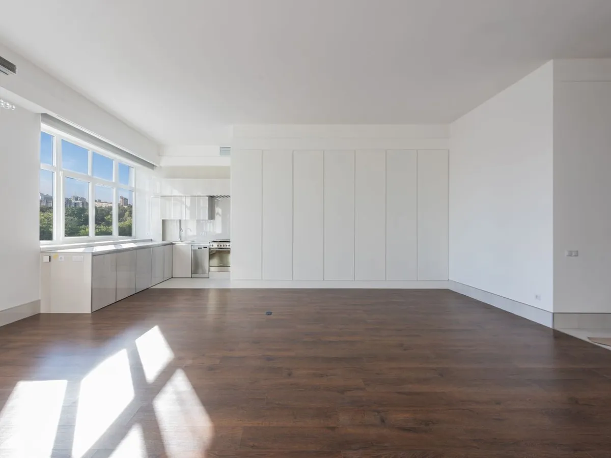 Bright, empty apartment with wood floors and sunlight through the windows